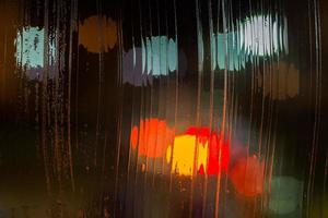 an abstract background night street lights bokeh through wet glass, close-up with selective focus photo