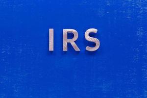 the word irs layed on blue painted board with thick silver metal aphabet characters photo