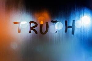 the word truth written on night wet window glass close-up with bokeh background photo