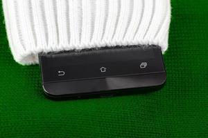 cellphone sticking out from knitted fabric like sweater or mittens photo
