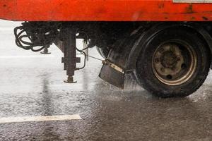 old orange utility truck moving on asphalt road under rainy day - close-up photo