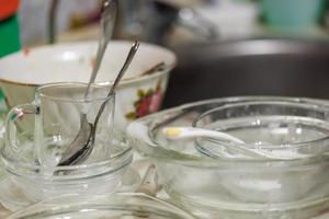 Utensilios de cocina sucios parcialmente cubiertos con detergente sud en proceso de lavado a mano foto