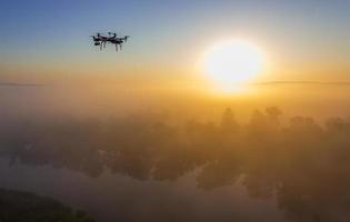 Hexacopter drone over foggy sunrise on river photo