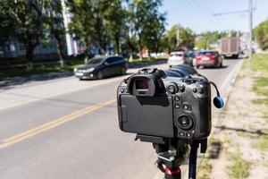 modern black professional mirrorless camera on tripod or monopod shooting city car traffic at summer day photo