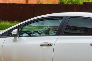 unidentifiable blonde long hair woman driving white car with paper coffee cup photo