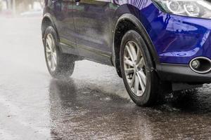 blue suv rushes on wet autumnal asphalt road photo