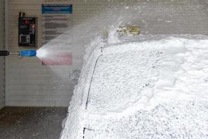 un proceso de aplicación de jabón sud en la estación de lavado de autos - cierre con enfoque selectivo foto