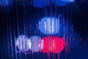 an abstract background of red and blue police lights bokeh trough wet glass at night close-up with selective focus photo