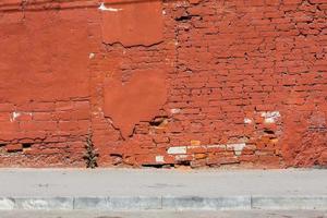 Pared de ladrillo antiguo con yeso pelado, todo pintado de naranja foto