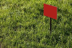 blank red sign mockup on green lawn background - close-up with selective focus photo