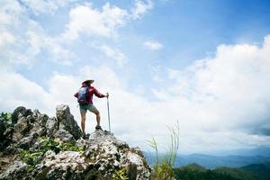 Young person hiking female standing on top rock, Backpack woman looking at beautiful mountain valley at sunlight in summer, Landscape with sport girl, high hills, forest, sky. Travel and tourism. photo