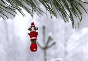 Christmas wooden toy bear on a snow-covered pine branch in the winter forest. Christmas background with copy space photo