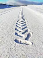 pattern of a footprint from a shoe in the snow extending into the distance photo