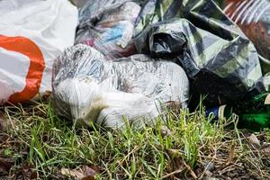 Garbage in plastic bags lies on grass. Environmental pollution. Ecological problems concept. photo