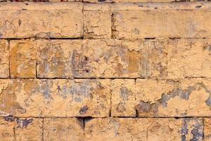 peeled off old orange paint on flat rough brick wall surface - full frame background and texture photo