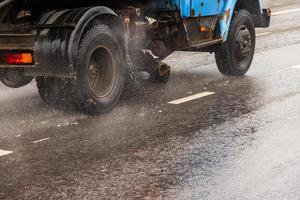 old utility truck moving on asphalt road under rainy day - close-up photo