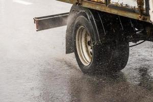 short box truck moving on a wet road with splashes during the day photo