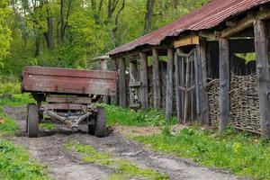 an old agricultural trailer stands next to the stables in summer, close-up with selective focus photo