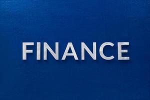 la palabra finanzas colocada con letras de metal plateado en una pizarra azul clásica en plano con composición central foto