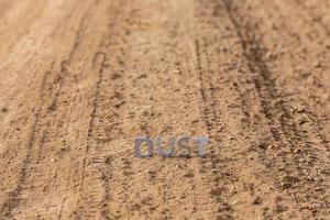 la palabra polvo de pie sobre la superficie de la carretera polvorienta en perspectiva lineal foto