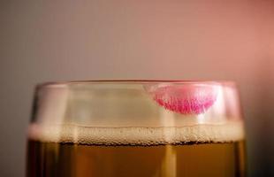 Woman Drinking Beer Concept. Closeup of Glass of Beer with Red Lipstick Mark. Feminine Mood photo