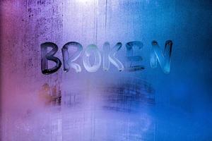 the word broken handwritten on wet window glass photo