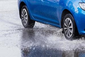 charco de cruce de coche azul con salpicaduras de agua en primer plano de la luz del día con enfoque selectivo. foto