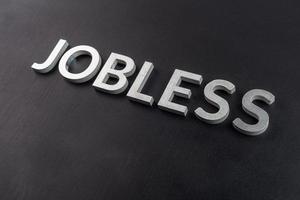 the word jobless laid with white scratched metal letters on flat black surface photo