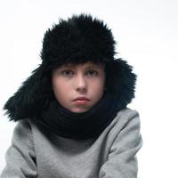 retrato de un niño con un sombrero de invierno con orejeras y una bufanda de punto sobre un fondo blanco. foto