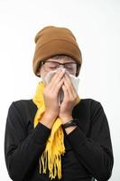 A boy wrapped in a scarf has a runny nose and blows his nose into a napkin. photo