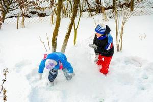 Two boys play snowballs, a fun game during the winter, a happy childhood for children. photo