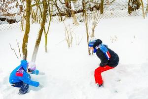 Two boys play snowballs, a fun game during the winter, a happy childhood for children. photo