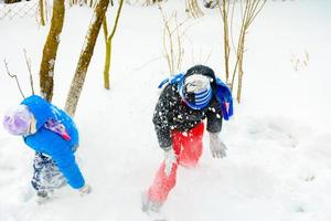 happy children playing snowballs, two brothers enjoying winter vacation, energetic game in the snow. photo