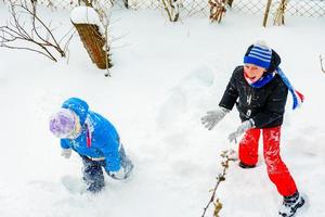 happy children playing snowballs, two brothers enjoying winter vacation, energetic game in the snow. photo