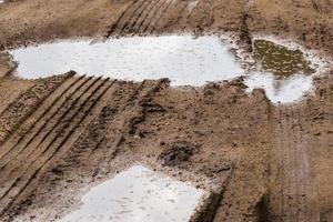 puddles in roadside dirt telephoto closeup shot with selective focus and blur photo