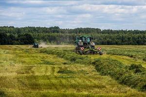 tula, rusia 30 de julio de 2019 tractor de heno verde en el campo de verano antes de la tormenta - teleobjetivo con enfoque selectivo foto