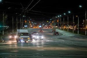 tula, rusia 22 de abril de 2017 tráfico de invierno de noche oscura en la calle con iluminación de puente y rieles foto