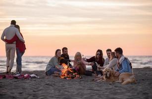 Couple enjoying with friends at sunset on the beach photo