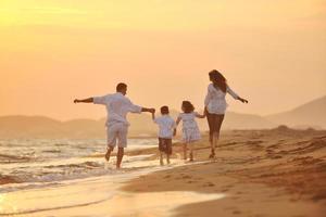 familia joven feliz divertirse en la playa al atardecer foto