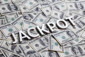 The word JACKPOT laid with aluminium letters on the US dollar banknotes background - with selective focus photo