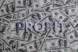 The word PROFIT laid with aluminium letters on the US dollar banknotes background - with selective focus photo