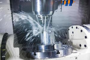 5-axis cnc milling machine at work with coolant under pressure and motion blur of streams.. photo