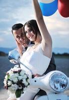 just married couple on the beach ride white scooter photo