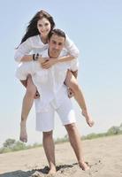 feliz pareja joven divertirse en la playa foto