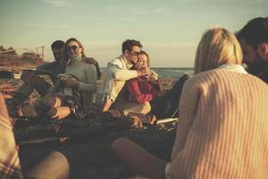 Couple enjoying with friends at sunset on the beach photo