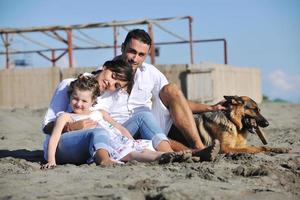 happy family playing with dog on beach photo