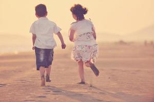 familia joven feliz divertirse en la playa al atardecer foto