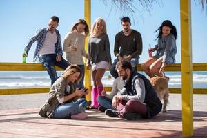 grupo de amigos divirtiéndose el día de otoño en la playa foto