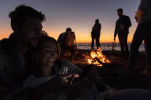 Couple enjoying bonfire with friends on beach photo