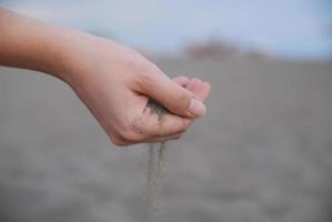 arena fina goteando a través de manos de mujer foto